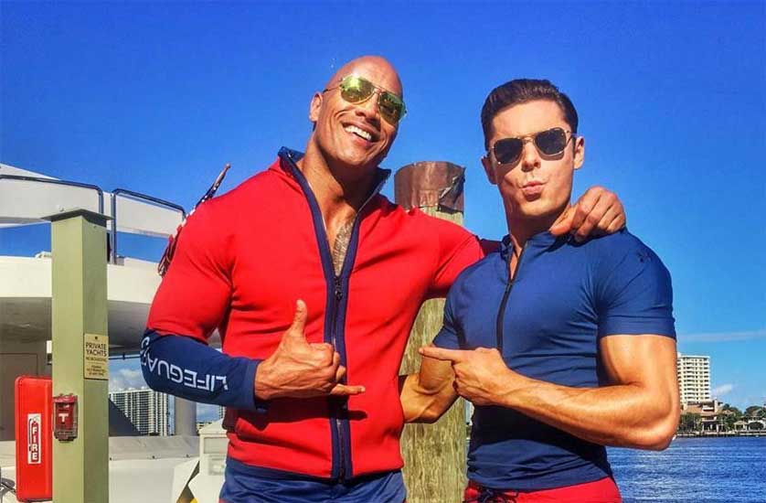 ‘Baywatch’ Teaser Trailer Puts The Rock And Zac Efron In A Comedic Beach Bod Showdown